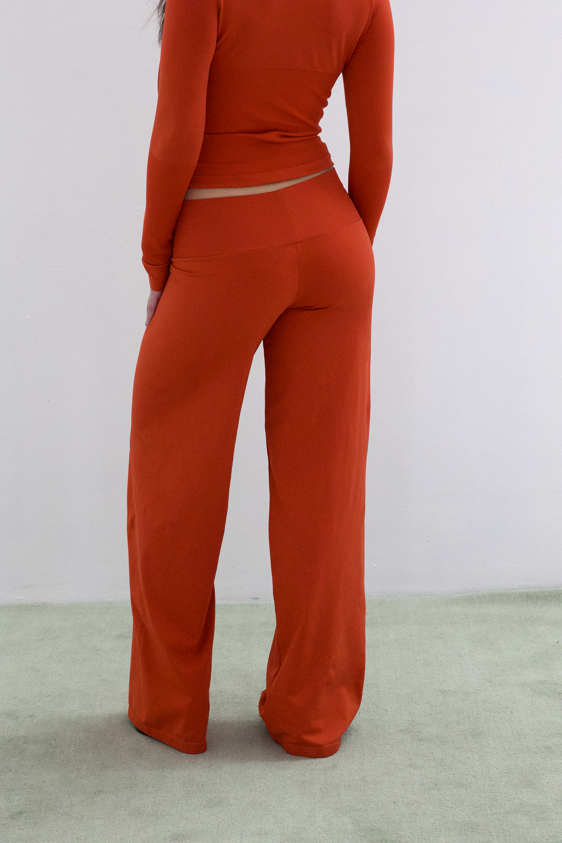 Woman wearing a red outfit with wide-leg pants on a light background
