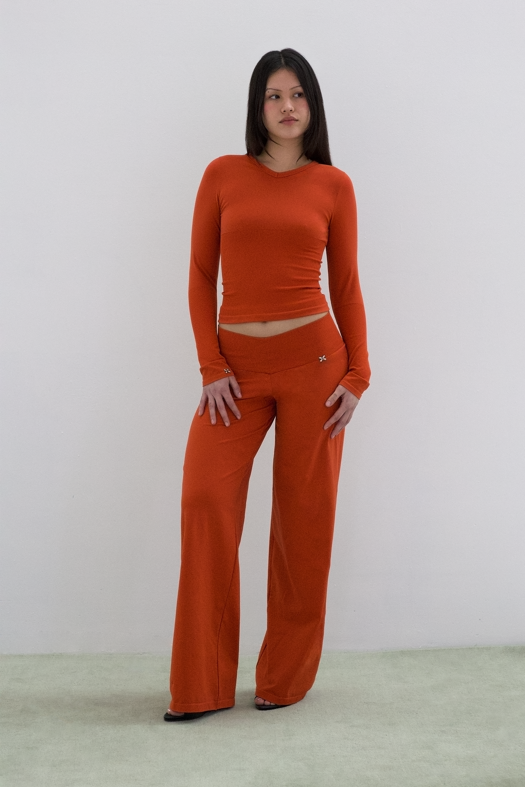 Woman wearing an orange outfit against a plain background